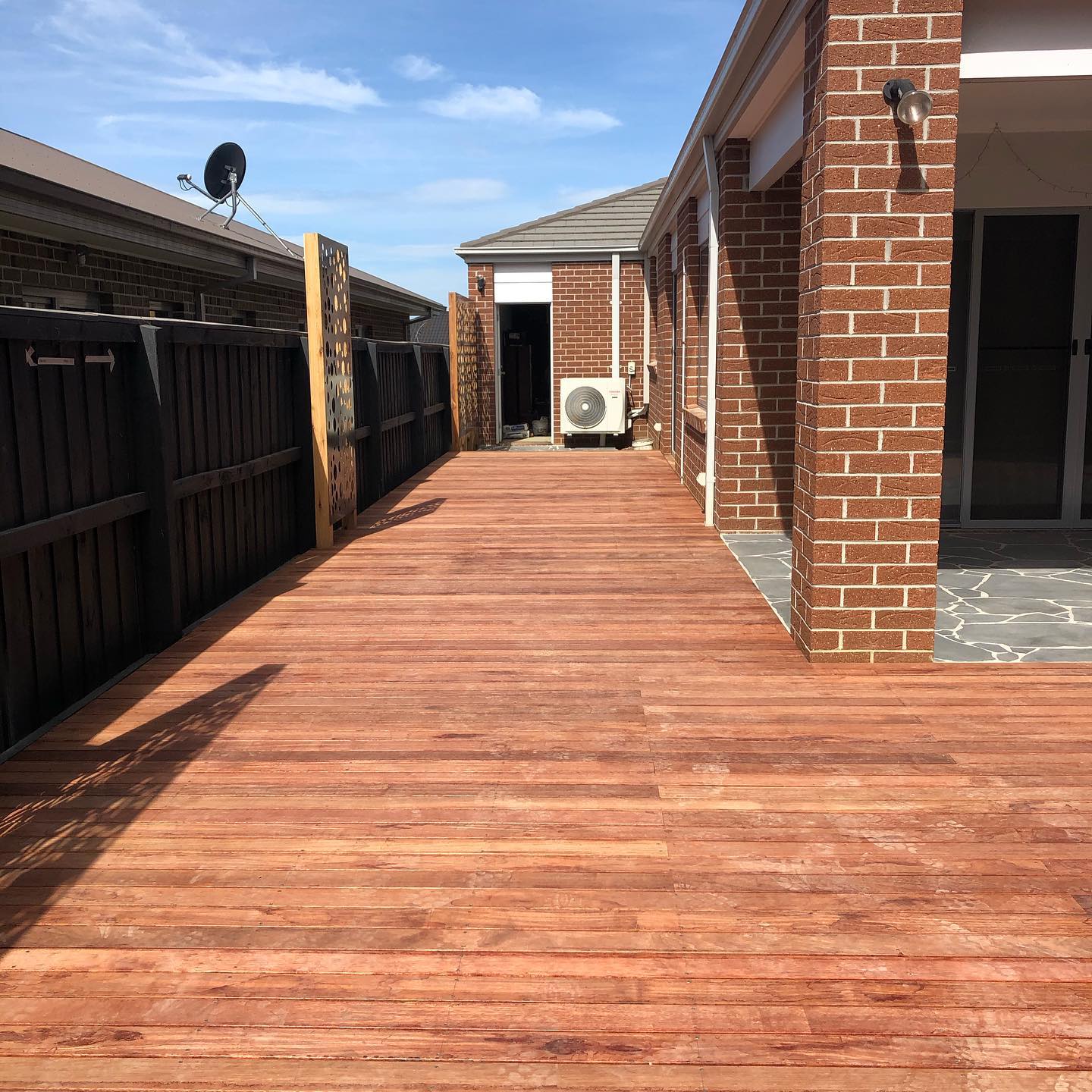 New timber deck running along the side of a brick house